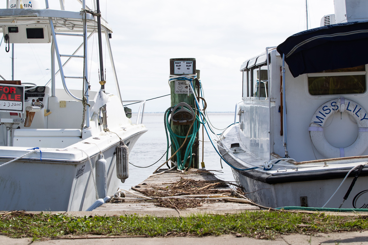 Debris from Hurricane Isaias remain between two docked boats in Apalachicola on Saturday, Oct. 10, 2026. City of Apalachicola Public Works staff work on cleanup and recovery efforts nearby.