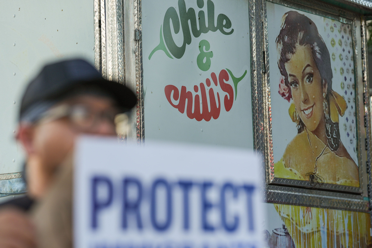 An activist holds a sign that reads “protect immigrants” during an “ICE Out: Let Us Live” rally held at the West Tennessee Street location of Chile & Chili’s, which has recently closed after workers were detained by ICE, Wednesday, Sept. 30, 2026.