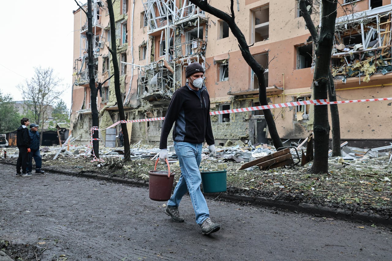 A person walks on a street surrounded by destroyed buildings.