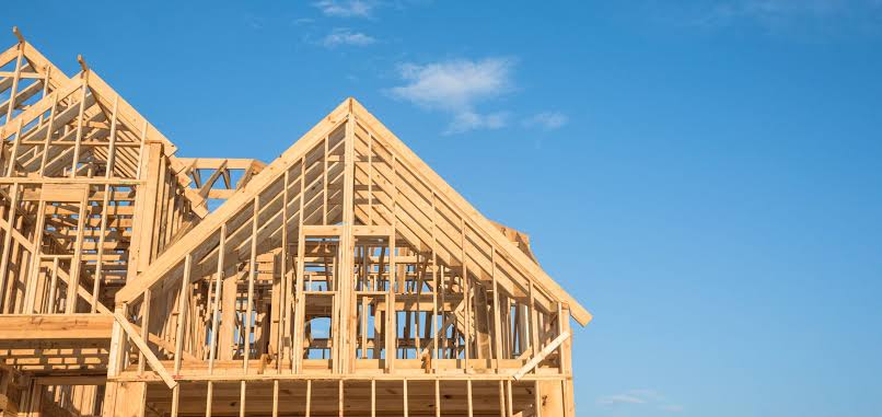 Wood framing is underway on a new single-family home under construction at a residential development site.