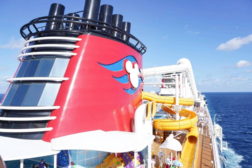 Port Canaveral, Florida - December 27, 2025: The smoke stack funnel and water slides on top of the Disney Cruise Line Treasure boat sailing away from Port Canaveral.