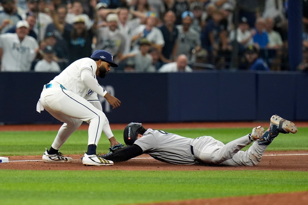 Tampa Bay Rays third baseman Junior Caminero, left, tags out New York Yankees' Austin Wells as Wells tries to stretch his double into a triple during the eighth inning of Game 1 of an American League Division Series baseball game Sunday, Oct. 4, 2026, in St. Petersburg, Fla.