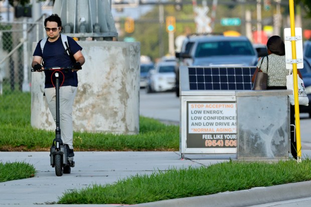 A man rides an e-scooter on the sidewalk on Sunrise Boulevard in Fort Lauderdale on Oct. 8, 2026. (Amy Beth Bennett/South Florida Sun Sentinel)