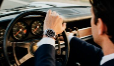 Driver wearing a chronograph watch at the wheel of a classic Porsche at Time To Drive festival