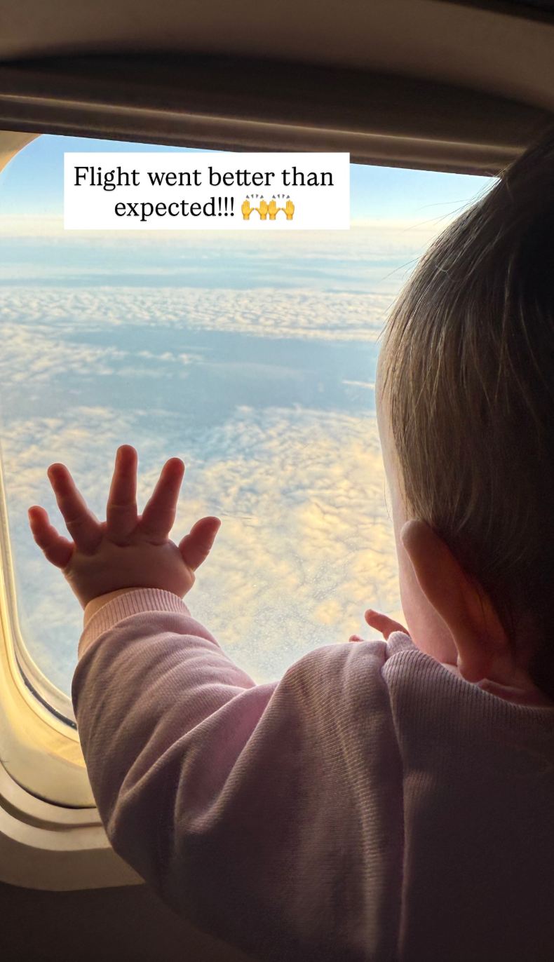 paige drummond holding baby sofia in front of airplane window