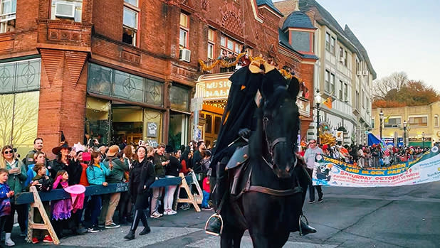 A person dressed as the headless horse rides a black horse during a parade through Sleepy Hollow