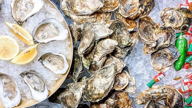 Raw oysters on ice with lemon wedges and tiny jars of Tabasco sauce
