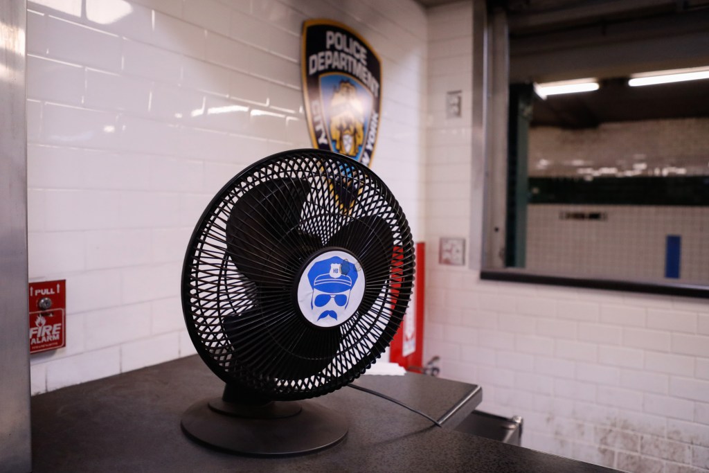 A fan sits on an NYPD desk inside an old newsstand on a West 4th Street subway platform.