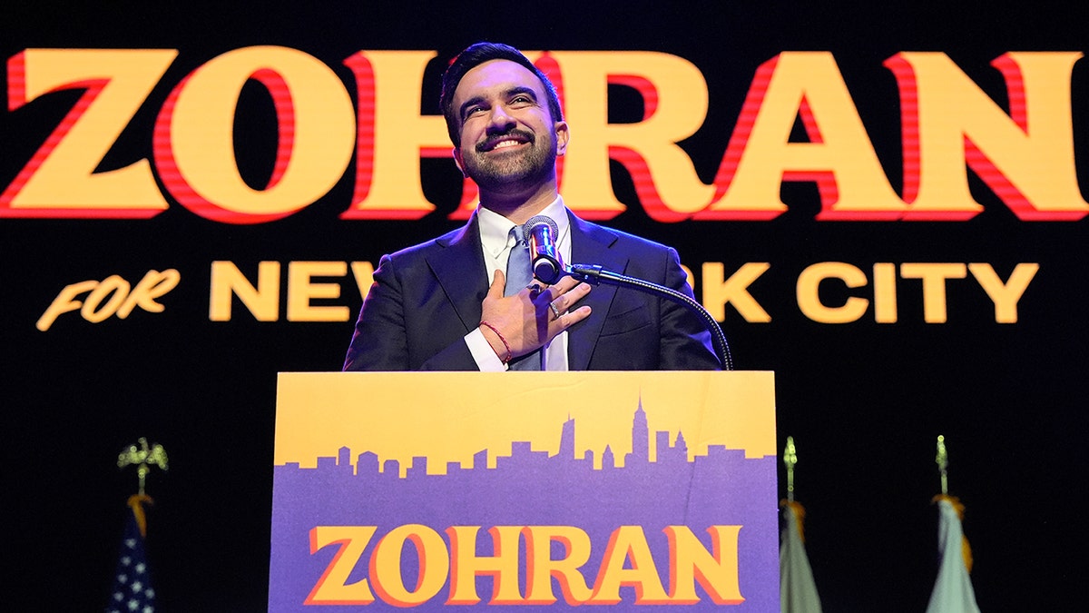 Zohran Mamdani delivers victory speech on Election night with his banner behind him.