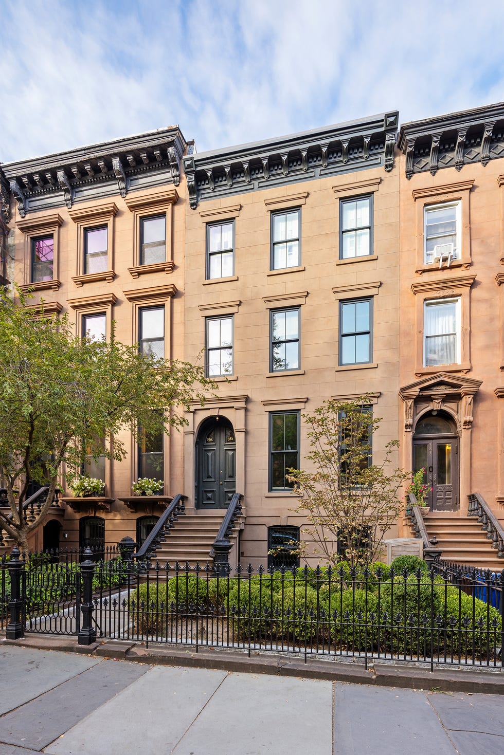 Historic brownstone buildings with prominent architectural features, front steps, and landscaping.