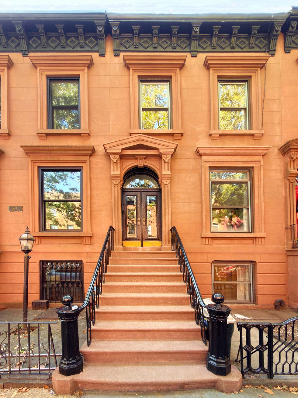 Historical brownstone facade with stairs and railing.