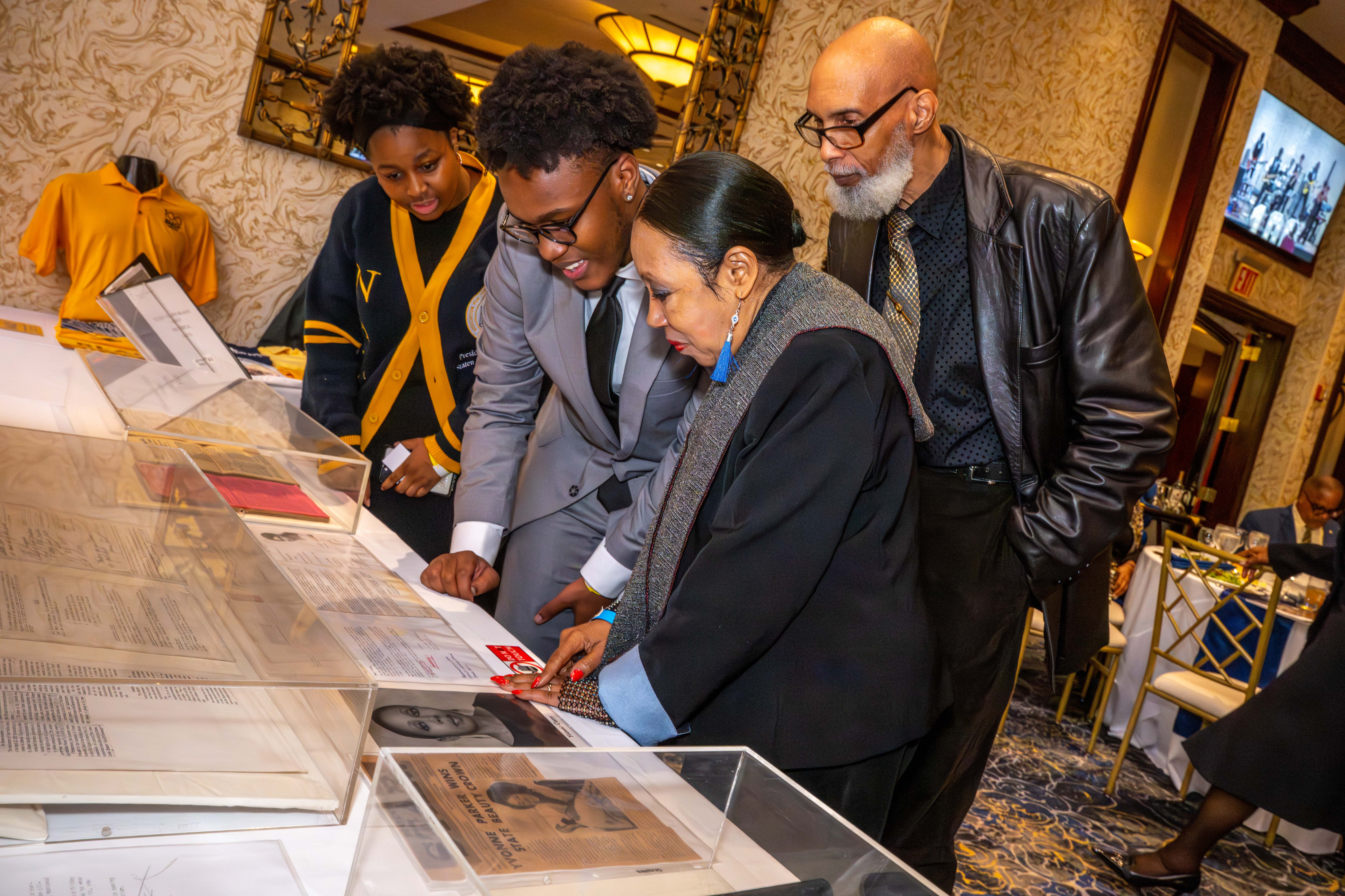 Yvonne Patricia Parker Curry, 76, who served as the Staten Island Branch Youth Council President in 1966, Xzayla Wilson, 16, the current Staten Island Branch Youth Council President, and Myles Hollingsworth, the NY State Conference Youth and College Division President, look at historical documents and photos at the Staten Island NAACP’s Freedom Fund Luncheon held at Nicotra’s Ballroom at the Hilton Garden Inn on Saturday, November 8, 2025, in Bloomfield. The milestone event marked 100 years of service to the community. (Owen Reiter for the Advance/SILive.com)