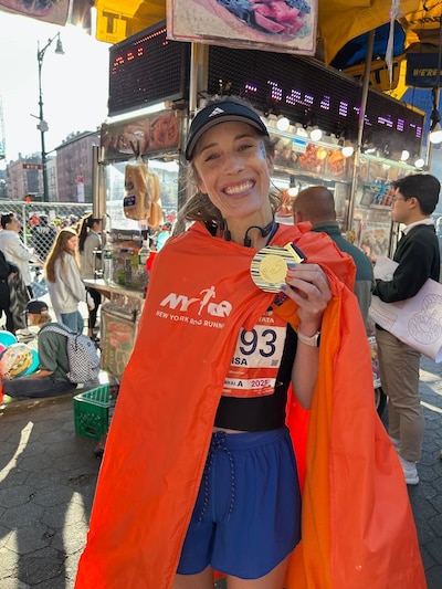 Marisa Donnelly holds up her medal after completing the New York marathon.