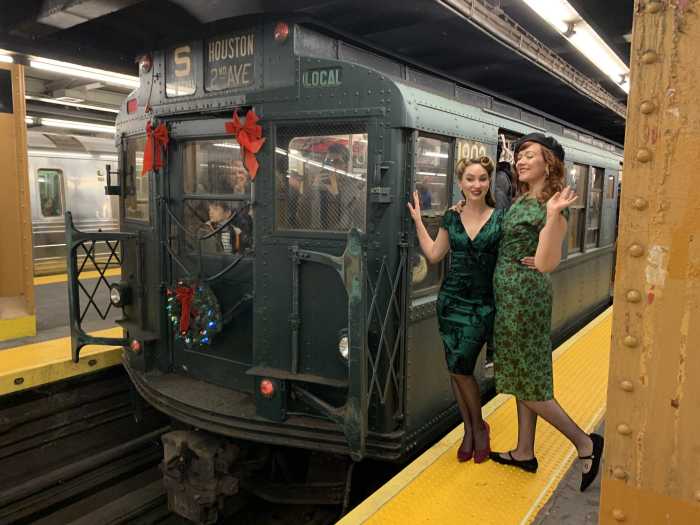 two women dressed in green dresses on a subway platform