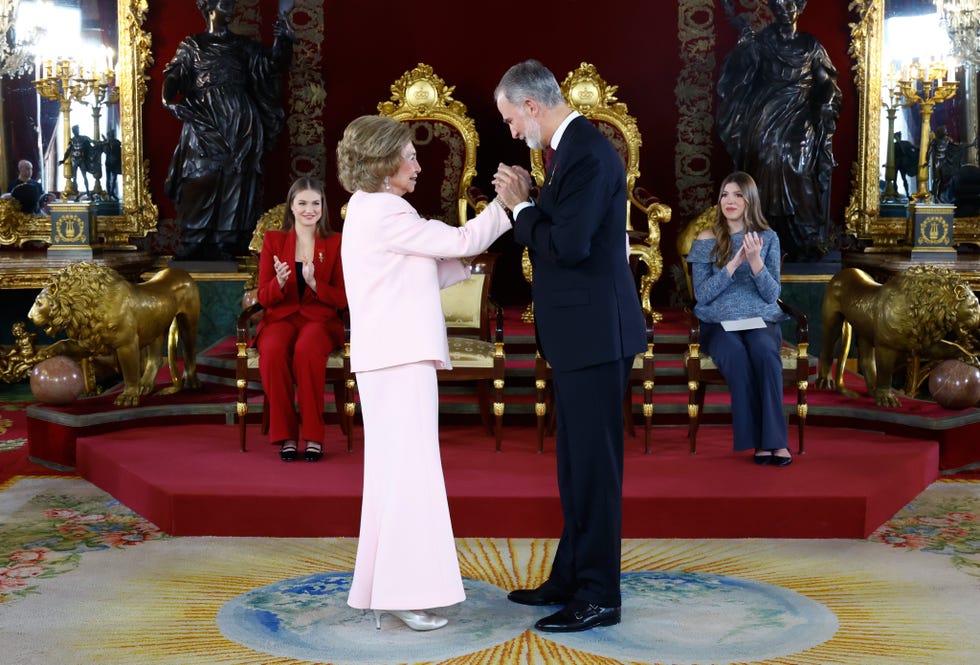 Ceremonial greeting between two formal figures in a lavish indoor setting