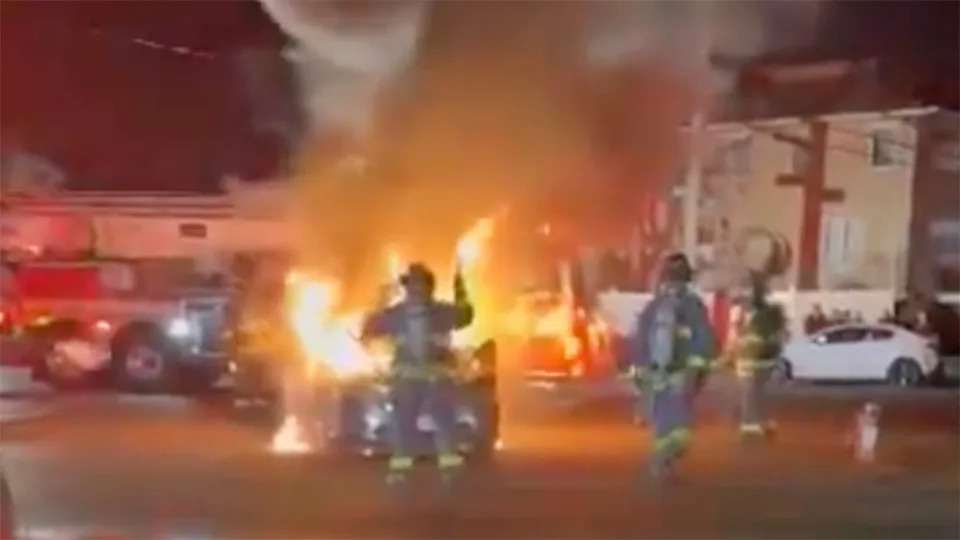 Firefights put out a car fire during a street takeover in New York City