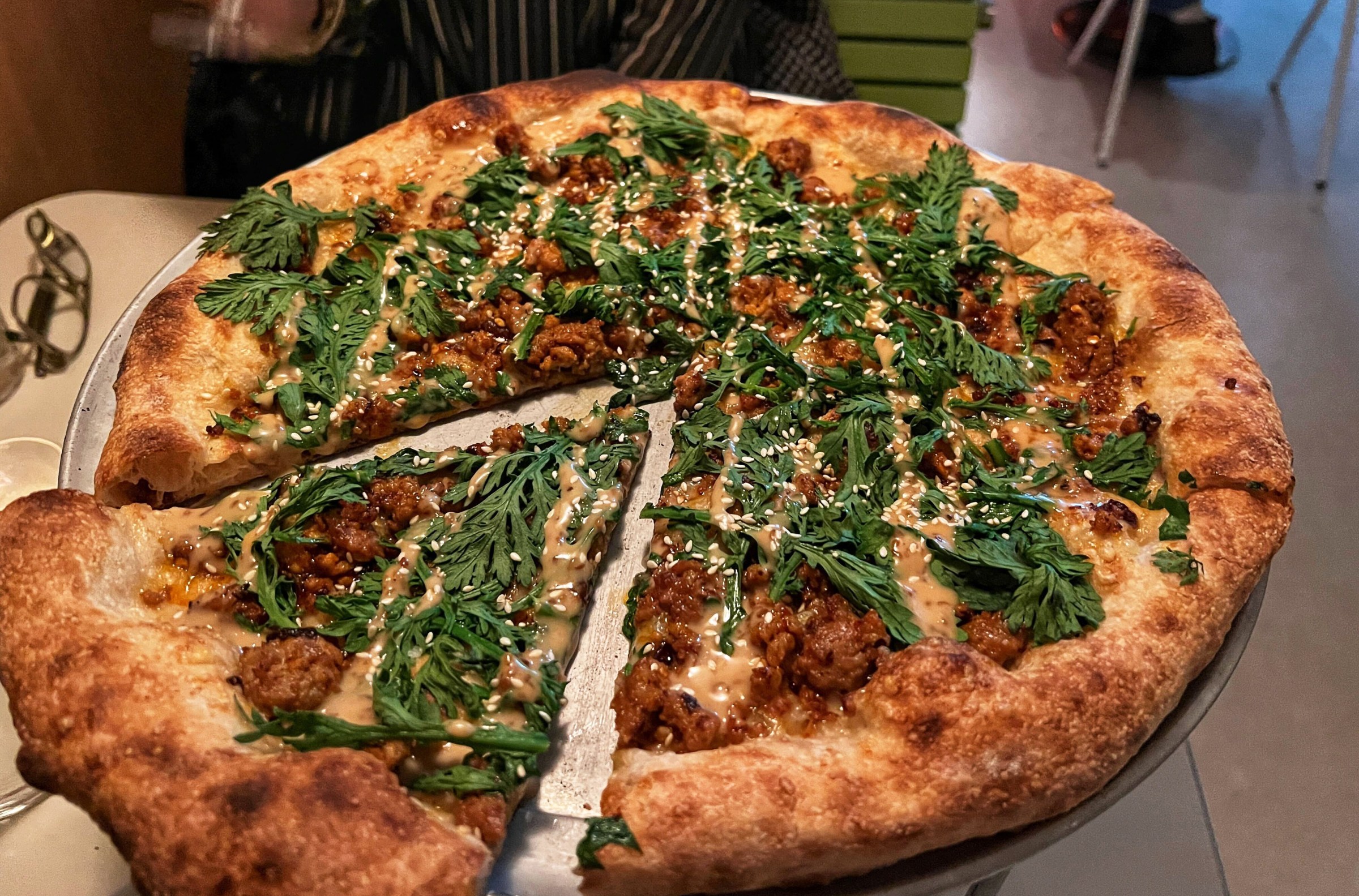 A big pizza pie with a slice being removed.