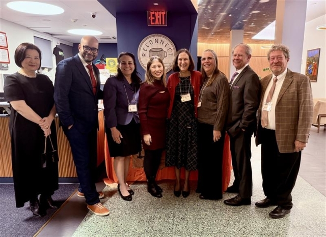 Group of men in women surrounded by a women who is holding an award 
