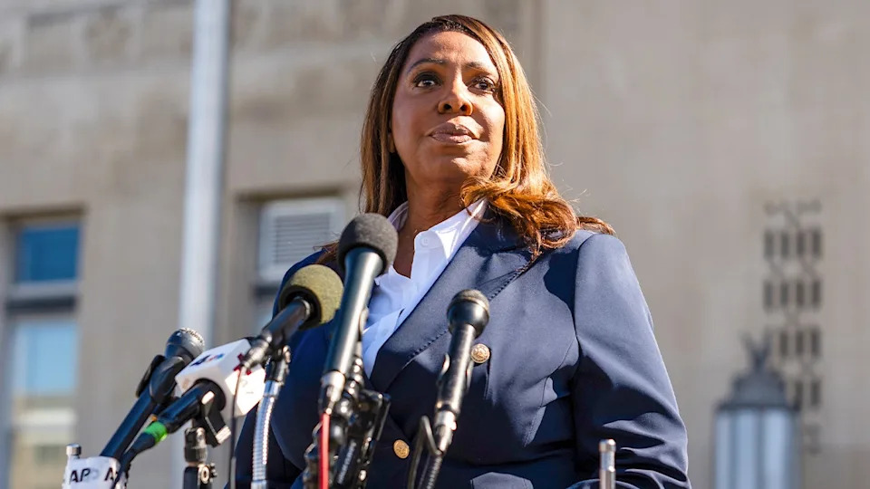 Letitia James stands in front of several microphones