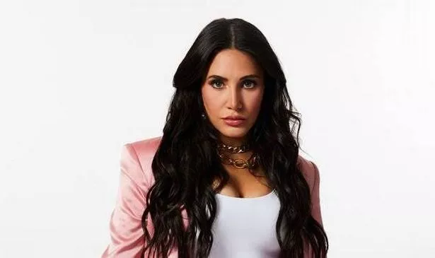 A woman in a pink jacket looks serious