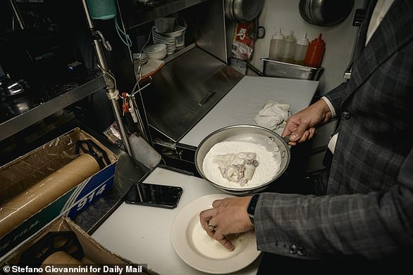 Vitolo is seen removing the squid from the milk marinade and putting it into the flour