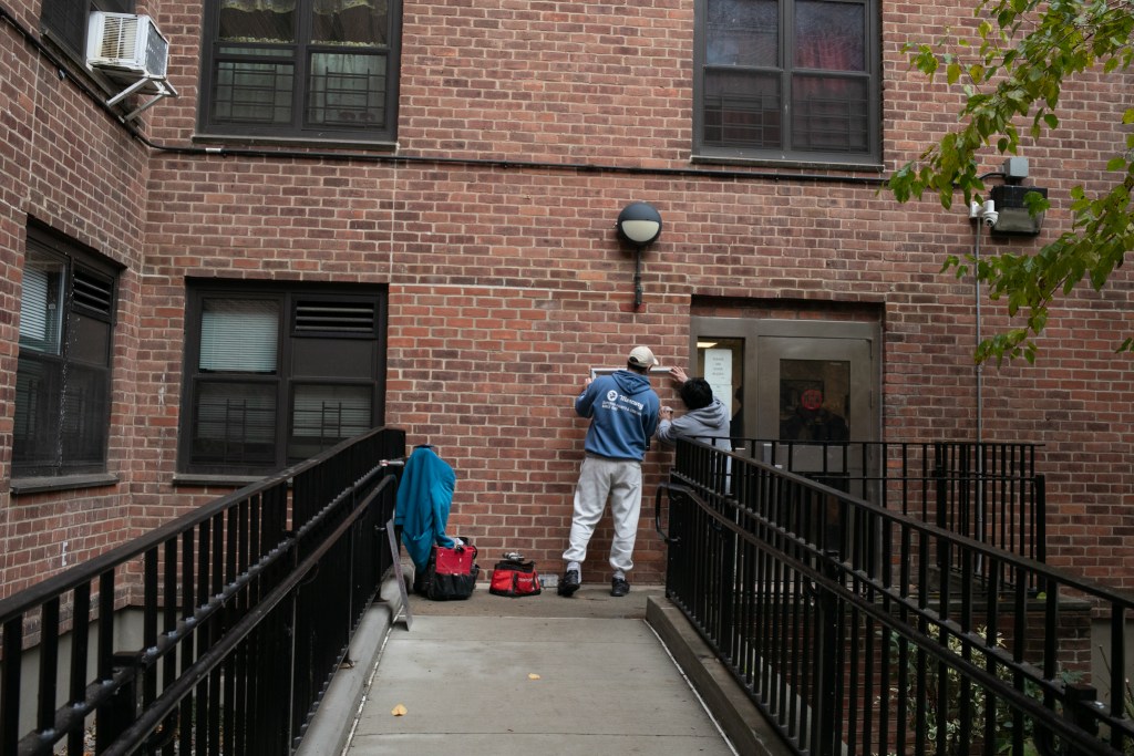 Workers hang a frame on the faced of the Boulevard Houses in Brownsville.