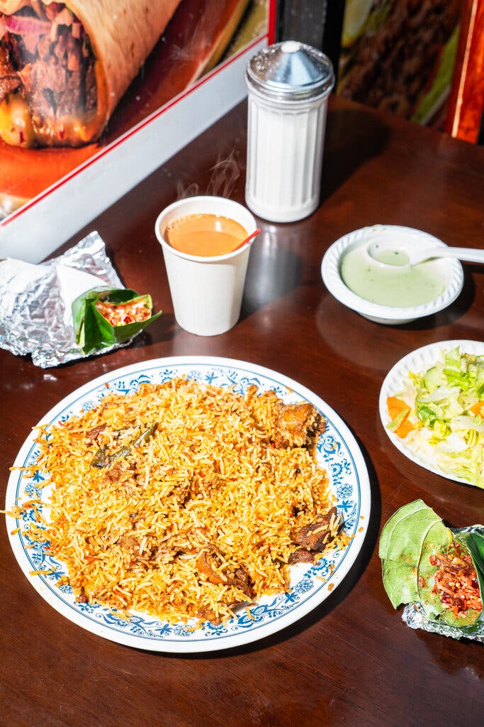 A plate of goat biryani sits next to two paans.