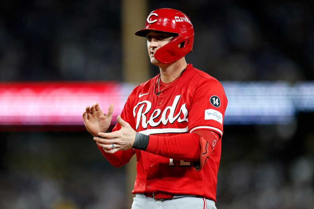Cincinnati Reds player Austin Hays in a red helmet and jersey reacts after hitting a single.