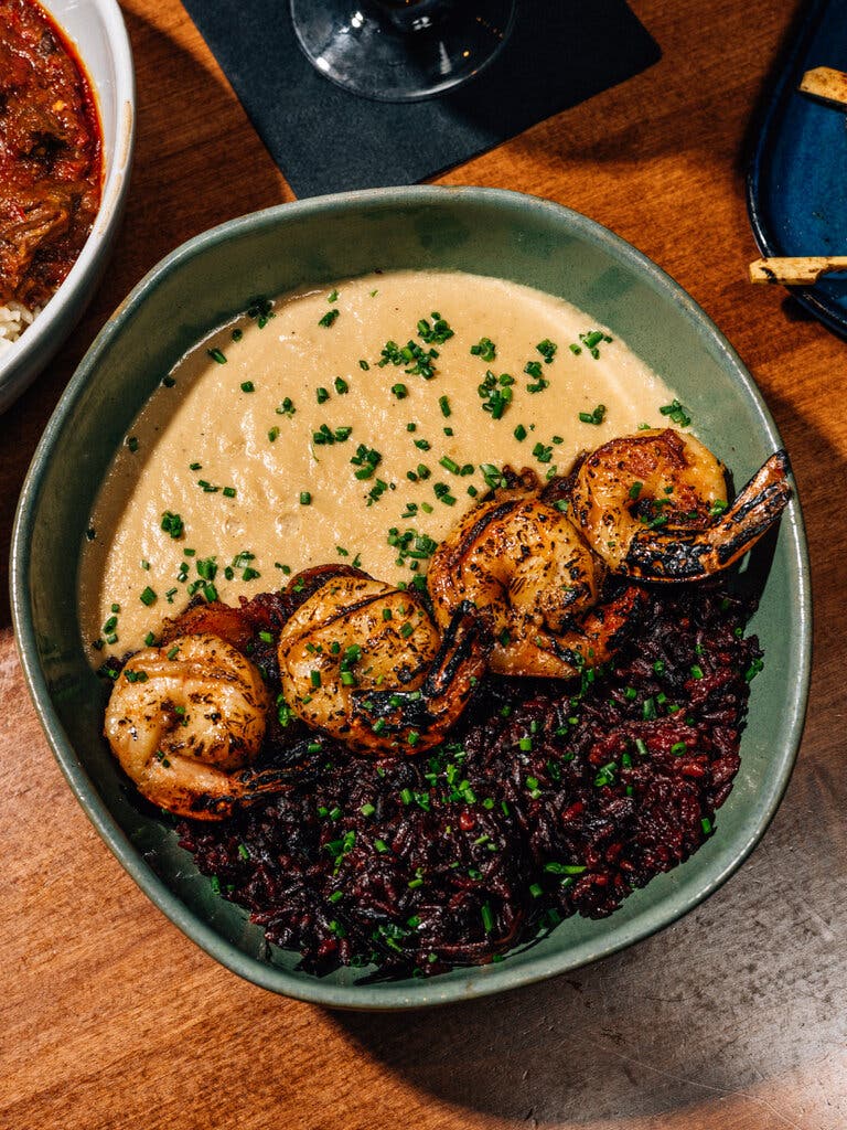 A bowl of curry and rice divided by grilled shrimp.