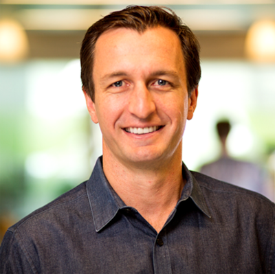A portrait of a man in a dark shirt looking at the camera.