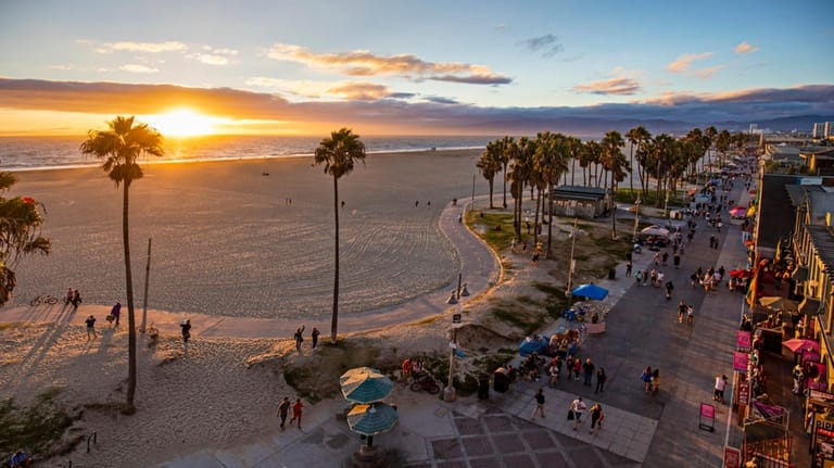 Visitors walk along Venice Beach at sunset.
