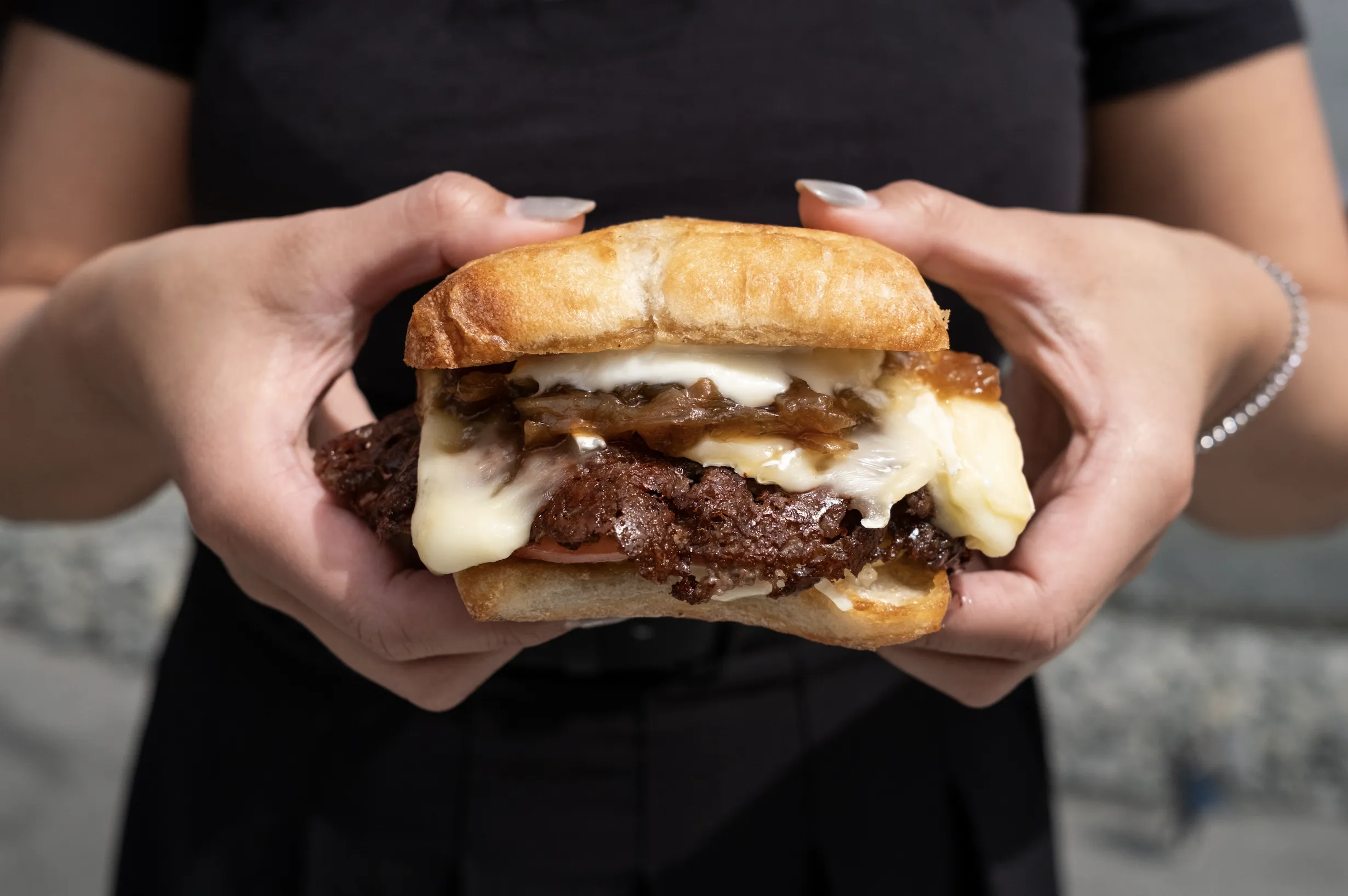 Hands holding a smashed burger