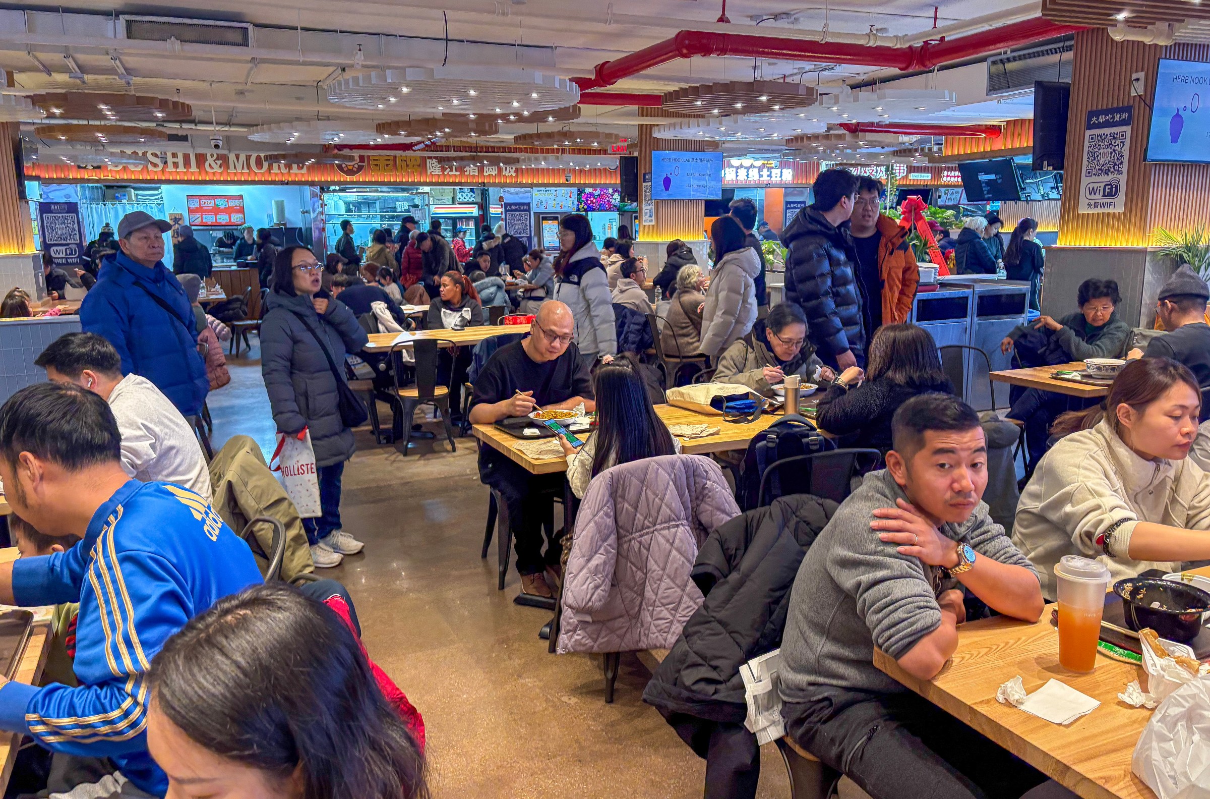 A food court with people seated at tables.