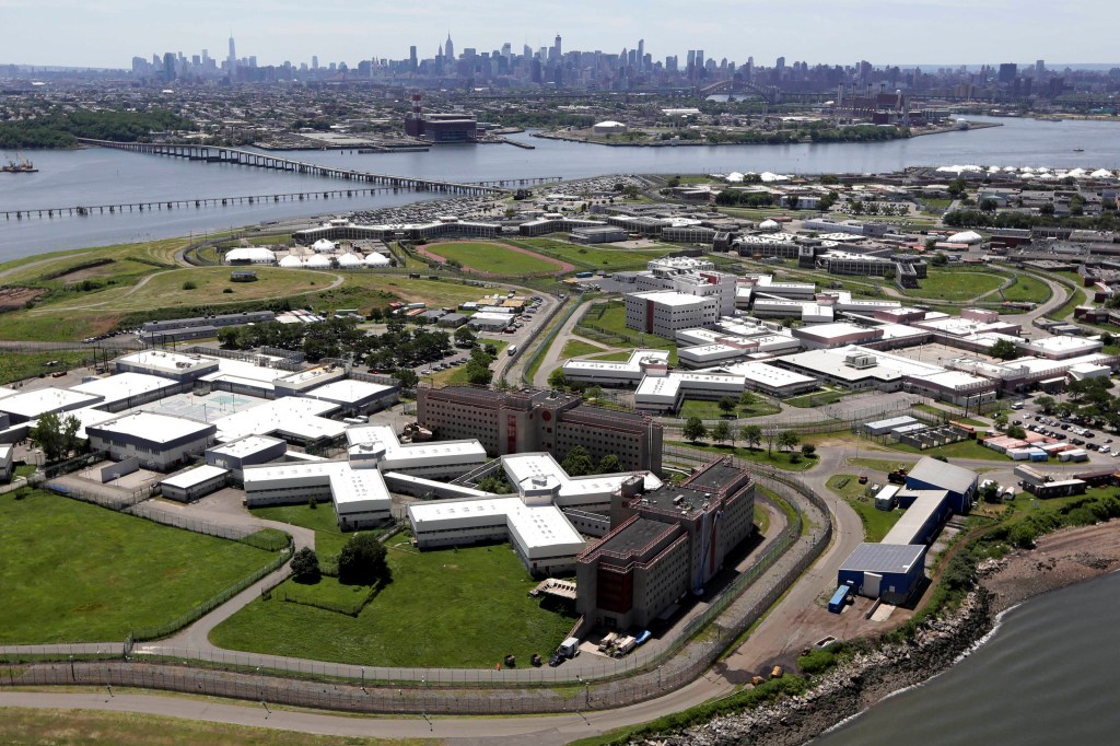 Aerial view of Rikers Island correctional facility with the New York City skyline in the background.