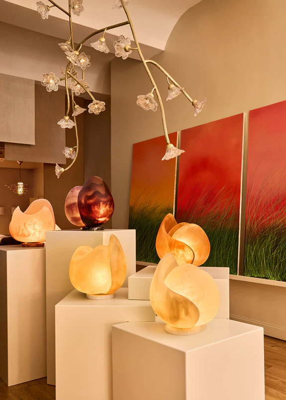 Artistic lighting display on white pedestals with flower-like ceiling lights and red-green artwork in the background.