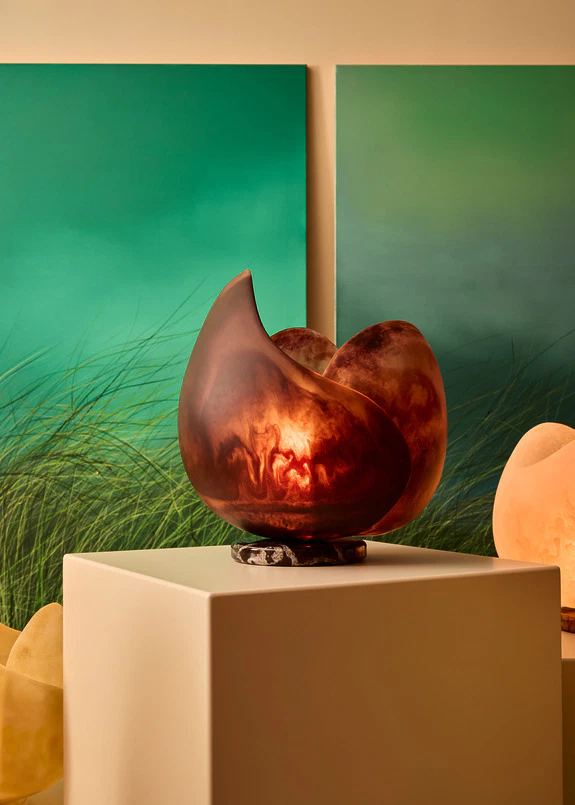 Abstract ceramic sculpture on display with green gradient paintings in the background