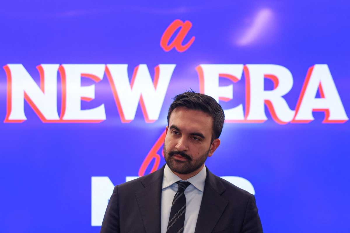 Zohran Mamdani speaking at podium in front of campaign banner