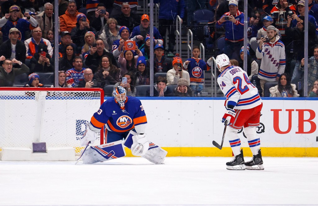 New York Islanders goalie David Rittich deflects the puck from New York Rangers player Carson Soucy.