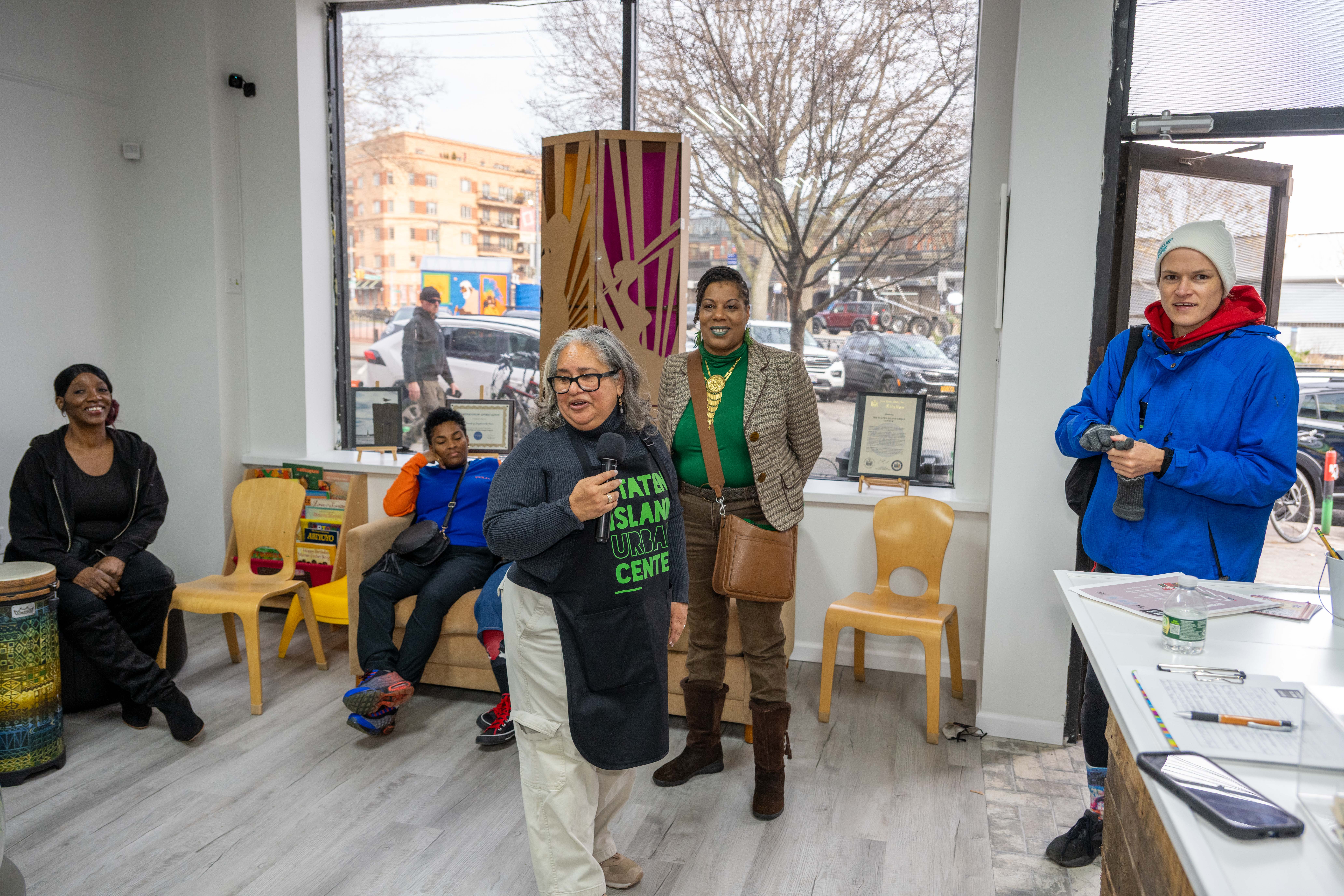 Kelly Vilar, center, founder and CEO, speaks at the grand opening of the Staten Island Urban Center’s new storefront at 206 Bay Street in Tompkinsville on Saturday, December 6, 2025. (Owen Reiter for the Advance/SILive.com)