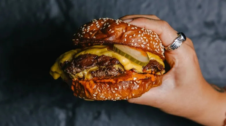 A hand holding The Legendary Burger from Nowon in NYC