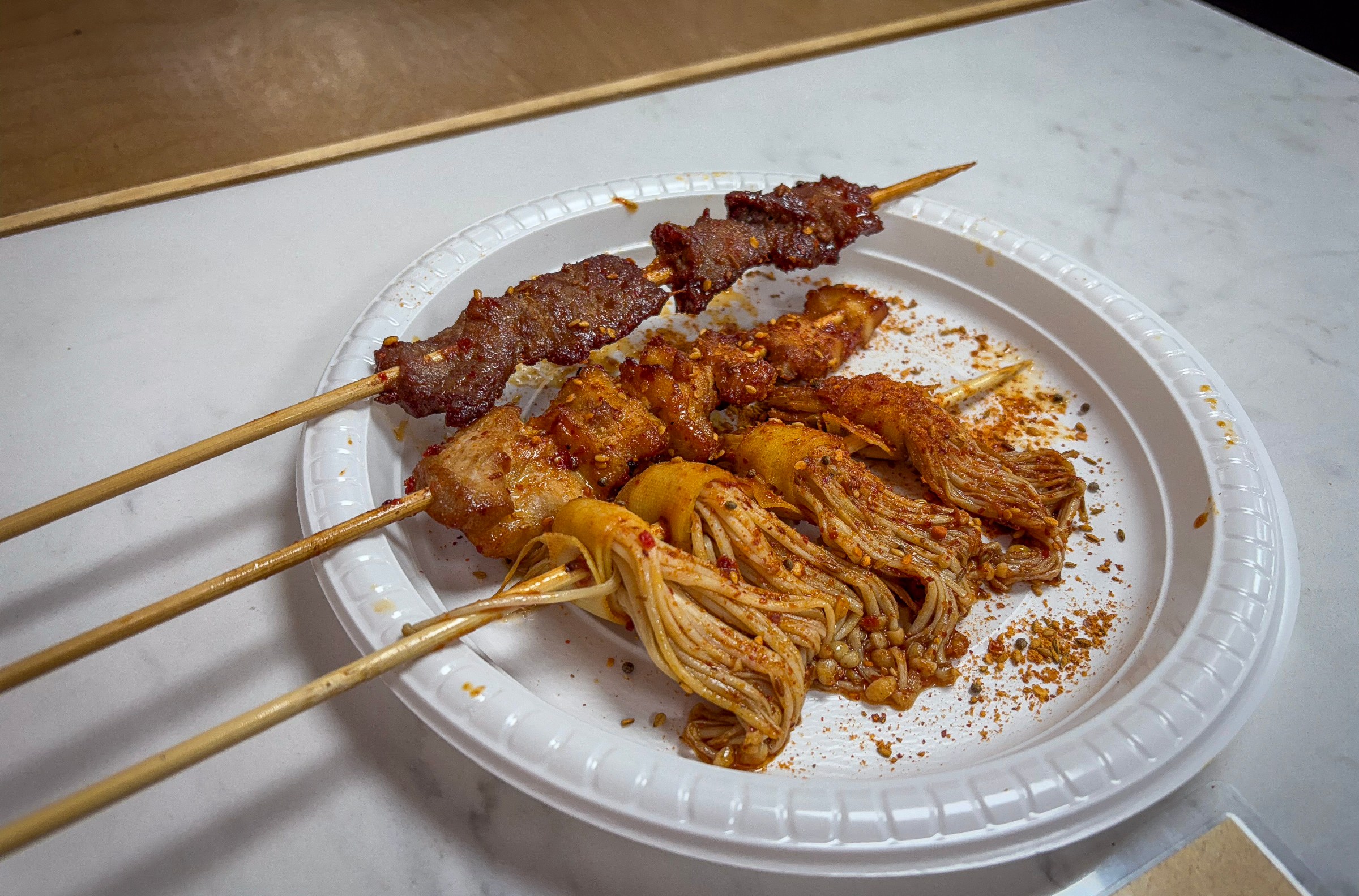 A plate of skewered meats and mushrooms.