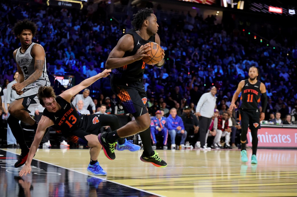 New York Knicks player Og Anunoby looking to pass as San Antonio Spurs player Tyler Kolek falls during a basketball game.