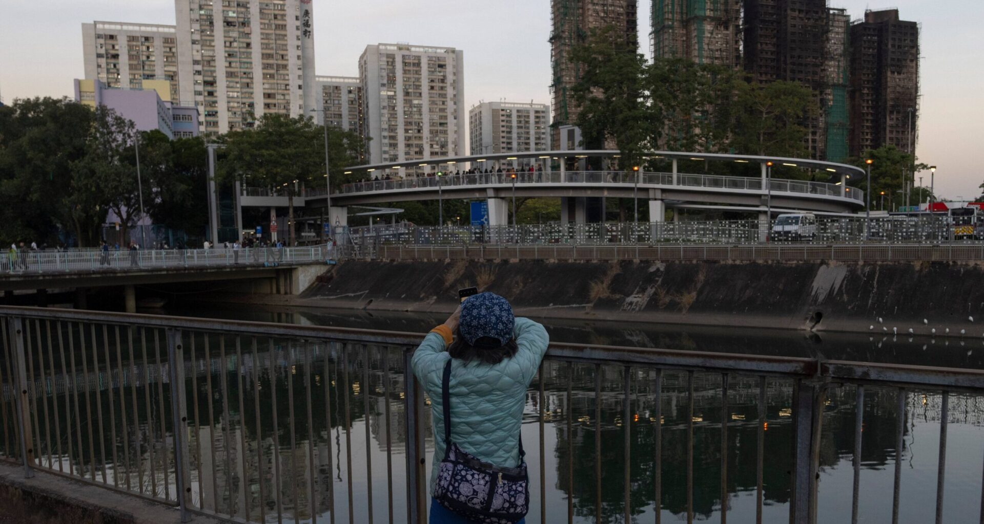 A woman takes photos of the charred buildings after a deadly fire that started Wednesday at Wang Fuk Court, a residential estate in the Tai Po district of Hong Kong's New Territories, Friday, Nov. 28 2025. Photo: Ng Han Guan/AP