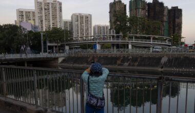 A woman takes photos of the charred buildings after a deadly fire that started Wednesday at Wang Fuk Court, a residential estate in the Tai Po district of Hong Kong's New Territories, Friday, Nov. 28 2025. Photo: Ng Han Guan/AP