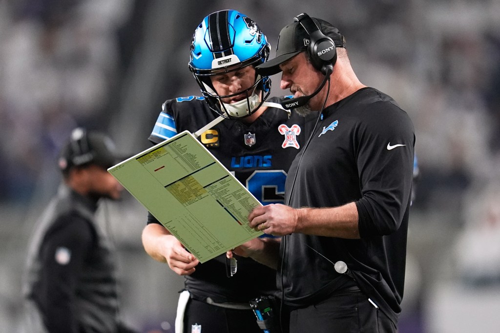 Detroit Lions quarterback Jared Goff, left, speaks with head coach Dan Campbell during the first half of an NFL football game against the Minnesota Vikings, Thursday, Dec. 25, 2025, in Minneapolis.
