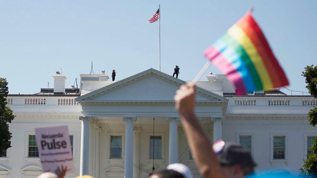 A protestor holds up a pride flag as marchers demonstrate in front of The White House.