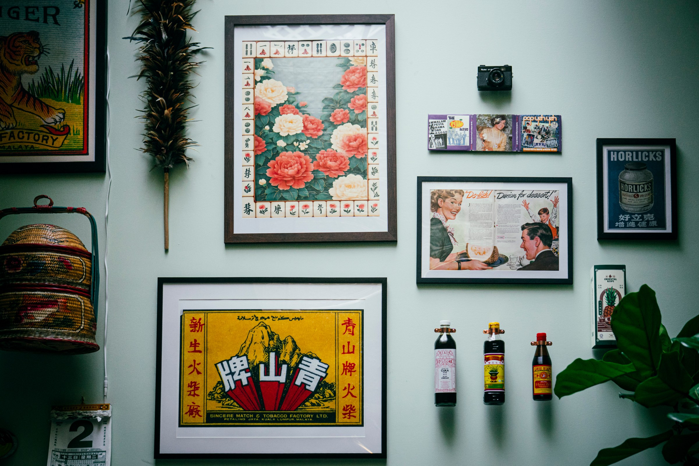 A wall with framed prints, photos, and bottles.