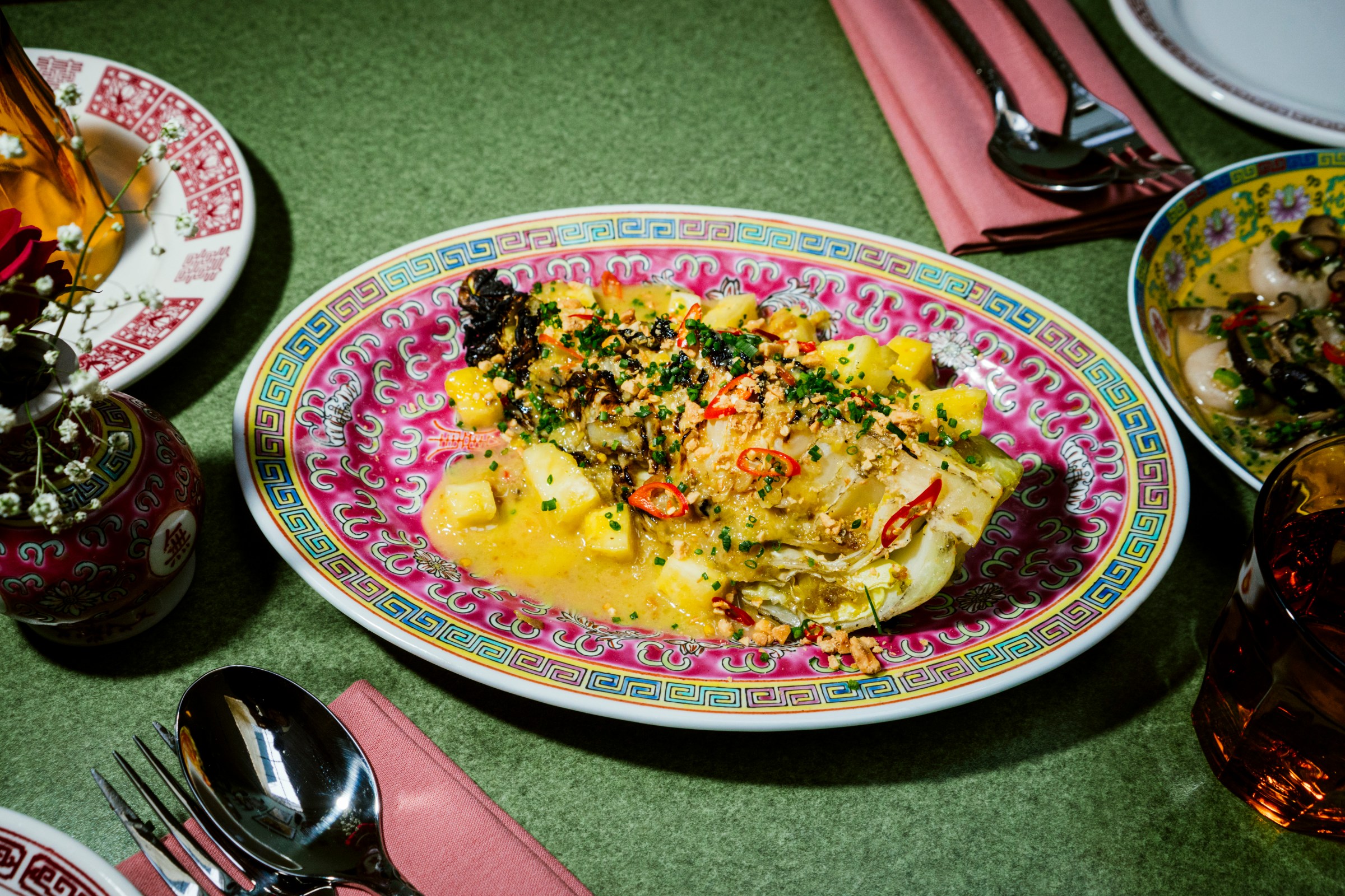 A plate of a cabbage wedge with broth and herbs.