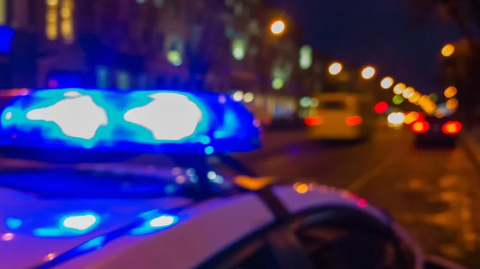Police car lights in night time, crime scene. Night patrolling the city. Abstract blurry image.