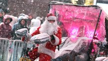 A pedicab tour guide, dressed in a Santa Claus costume, rides during a snowfall in Times Square on December 26, 2025, in New York City. New York, the US largest city, was bracing for up to 10 inches (25 centimeters) of snow overnight, the most in four years. (Photo by TIMOTHY A. CLARY / AFP via Getty Images)